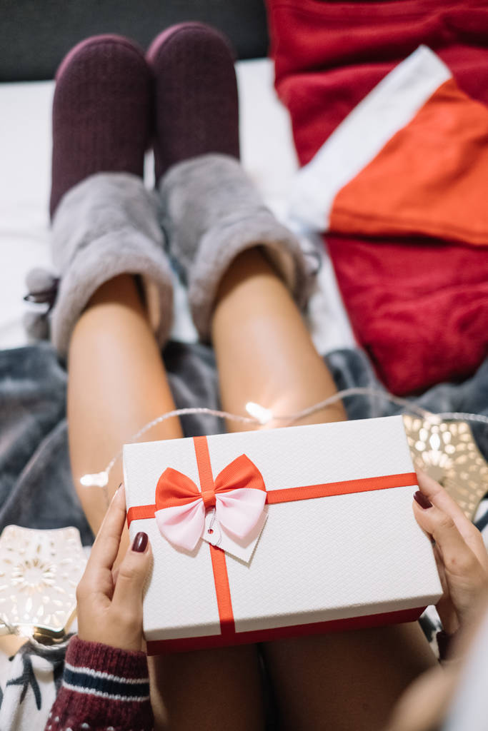 Çıplak kadın bacakları, terlikleri ve Noel hediyesi. - Fotoğraf, Görsel