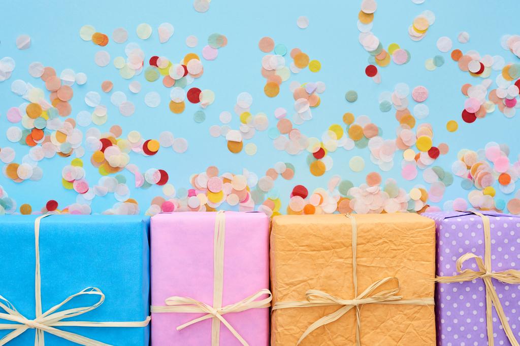 vista superior de coloridas y envueltas cajas de regalo cerca de confeti en azul
  - Foto, Imagen