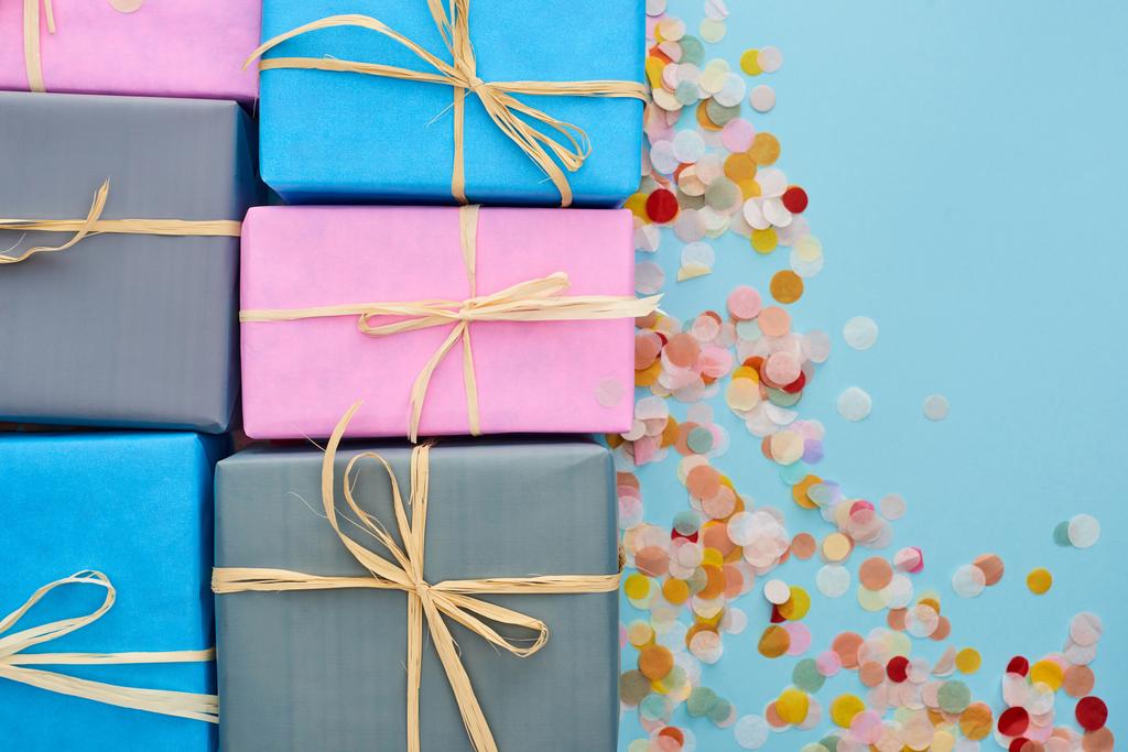 вид сверху на красочные и завернутые подарки рядом с конфетти на голубом
  - Фото, изображение