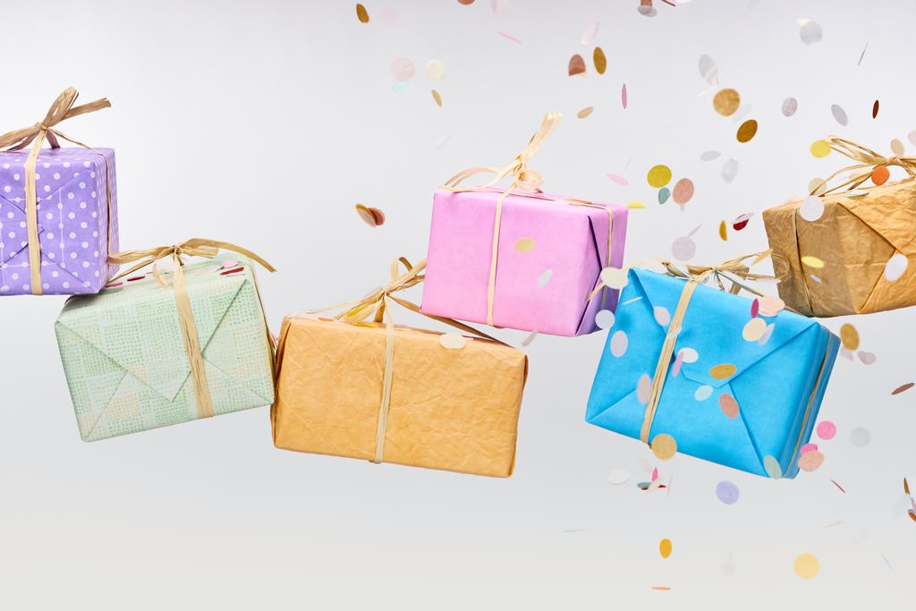 падаючий барвистий конфетті біля загорнутих подарунків на білому
 - Фото, зображення