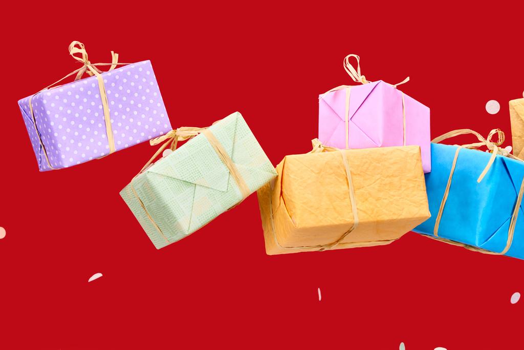 κομφετί κοντά πολύχρωμα κουτιά δώρων στο κόκκινο  - Φωτογραφία, εικόνα