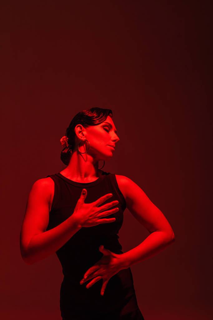 黒のドレスを着た官能的なダンサーが赤い照明で暗い背景でタンゴを演奏 - 写真・画像
