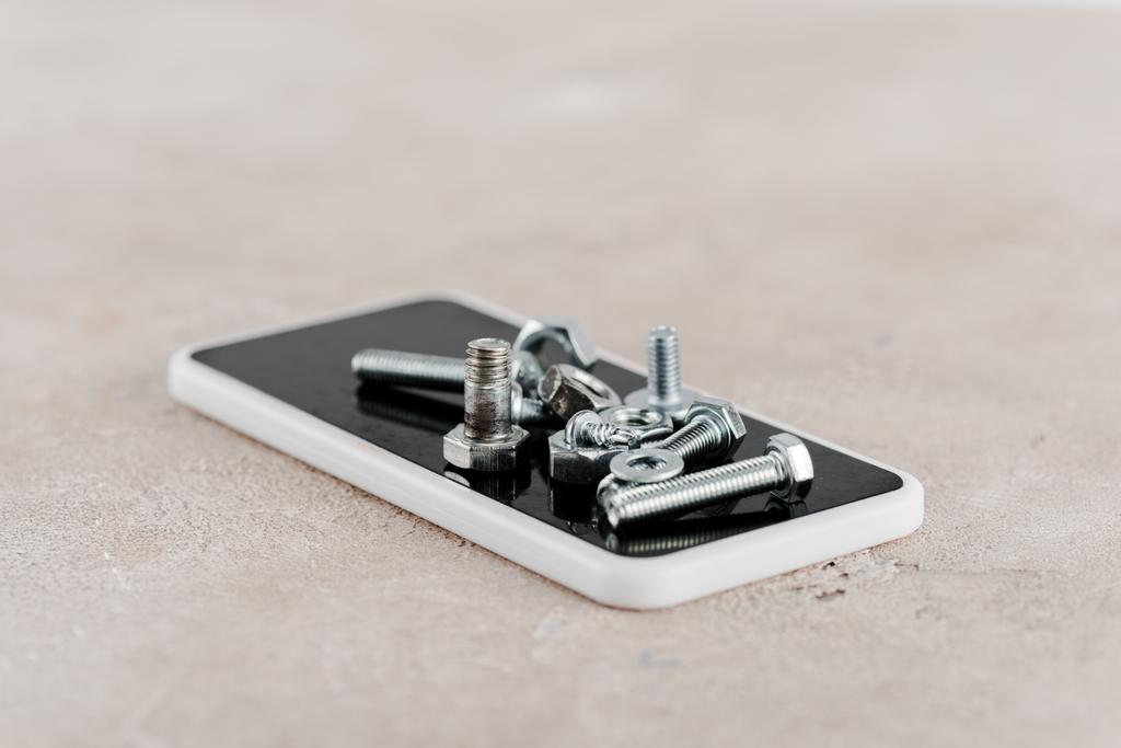 viti e bulloni in metallo su smartphone su sfondo grigio
 - Foto, immagini