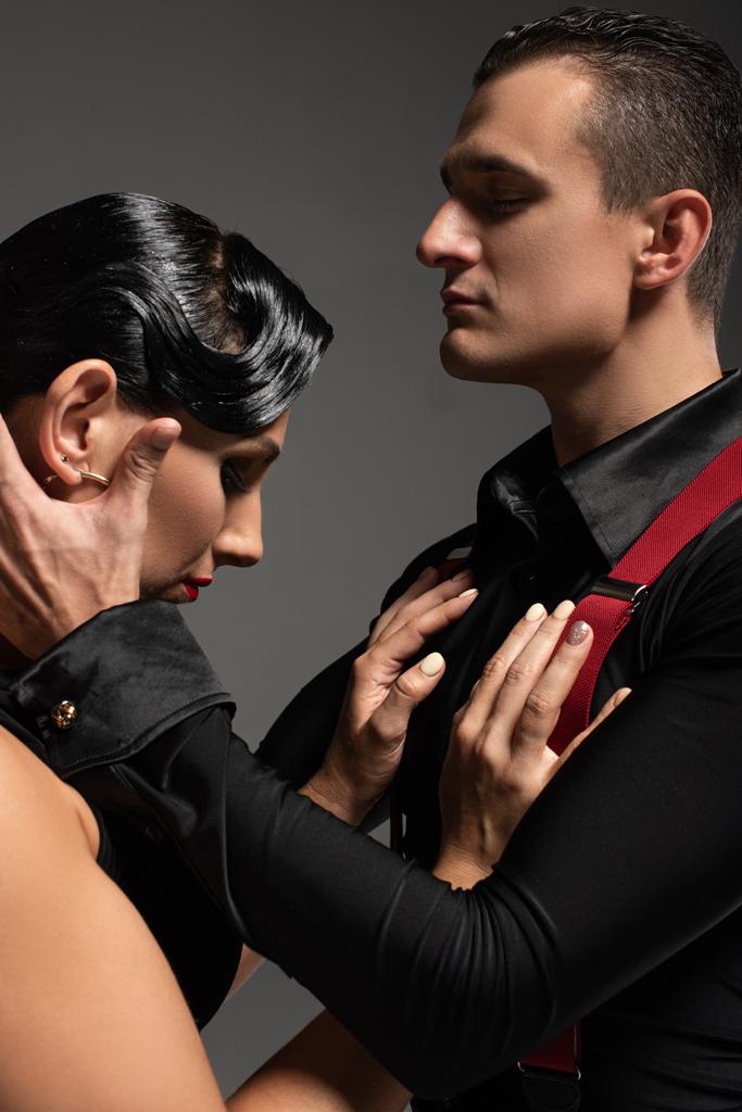 sensuele danser aanraken hoofd van mooie partner tijdens het uitvoeren van tango geïsoleerd op grijs - Foto, afbeelding