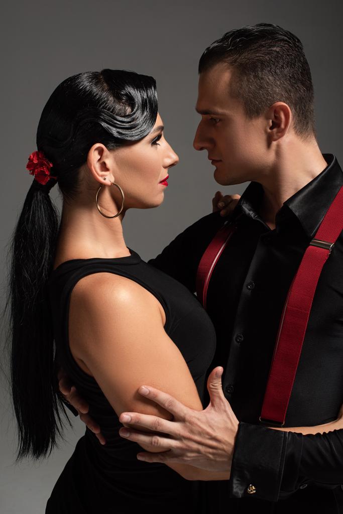 два страстных танцора, исполняющих танго лицом к лицу, изолированные на сером
 - Фото, изображение