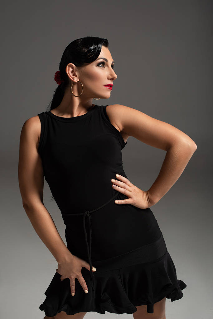 atractiva bailarina de tango en elegante vestido negro mirando hacia otro lado sobre fondo gris
 - Foto, Imagen