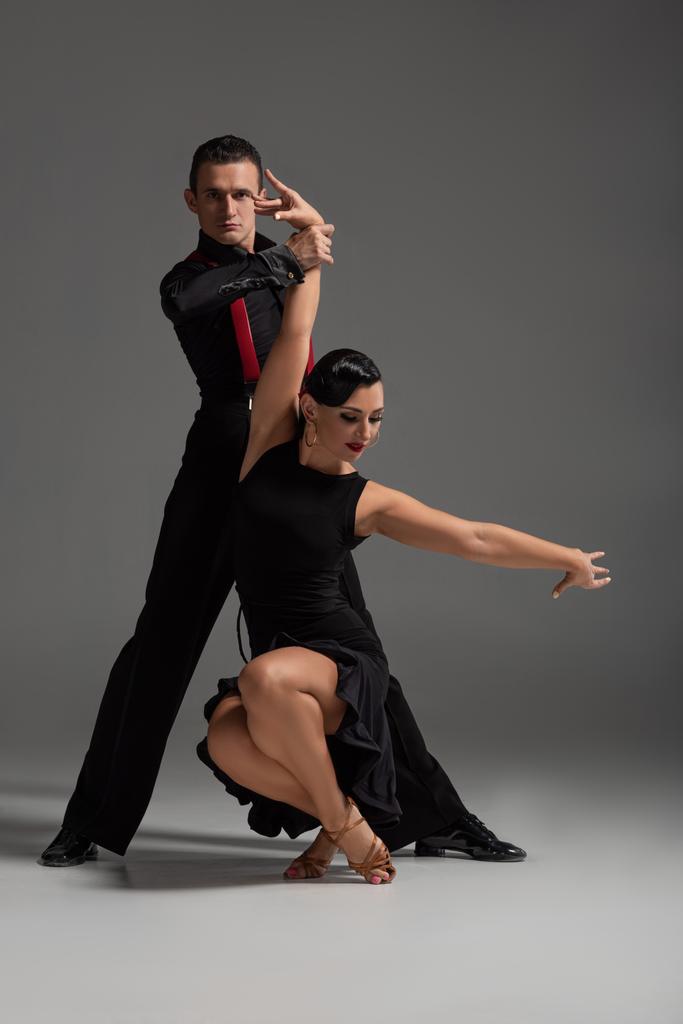 szenvedélyes táncosok fekete, elegáns ruházat tánc tangó szürke háttér - Fotó, kép