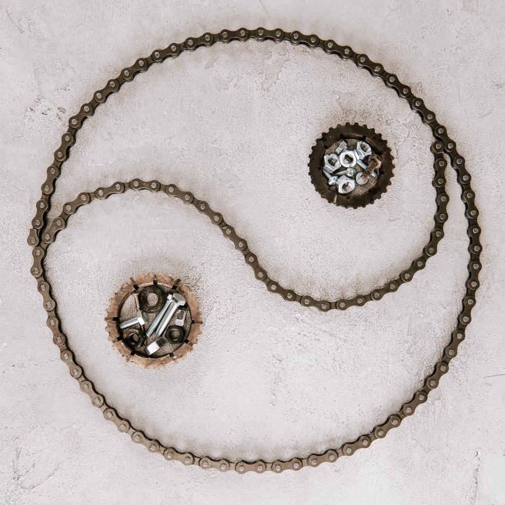 Ansicht von gealterten Zahnrädern und Schrauben aus Metall, die im Taijitu-Symbol auf grauem Hintergrund angeordnet sind - Foto, Bild