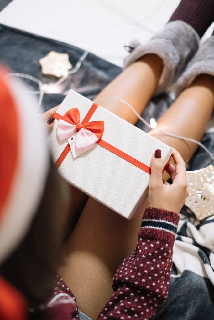Mädchen hält Geschenk mit Hausschuhen über die Beine - Foto, Bild