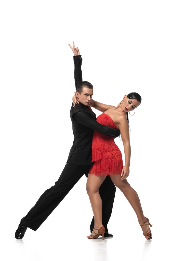 элегантный танцор показывает победный жест во время исполнения танго с красивым партнером на белом фоне
 - Фото, изображение
