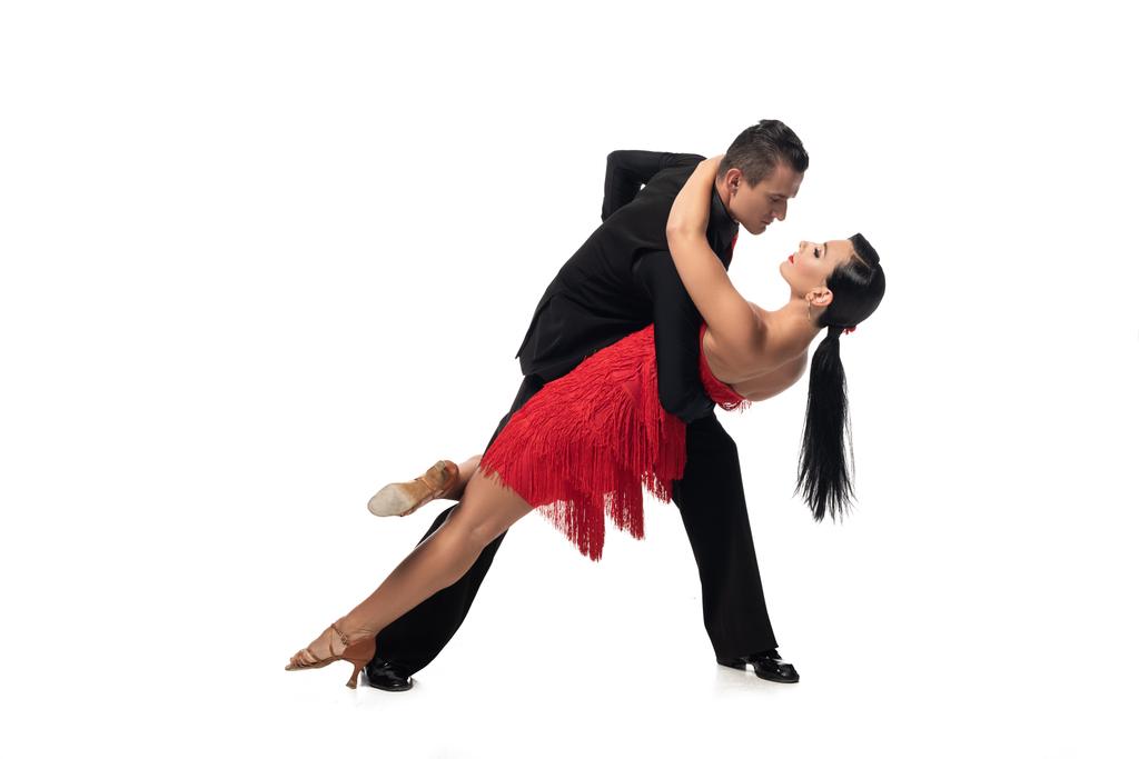 elegancki tancerz wspierający pięknego partnera podczas wykonywania tanga na białym tle - Zdjęcie, obraz