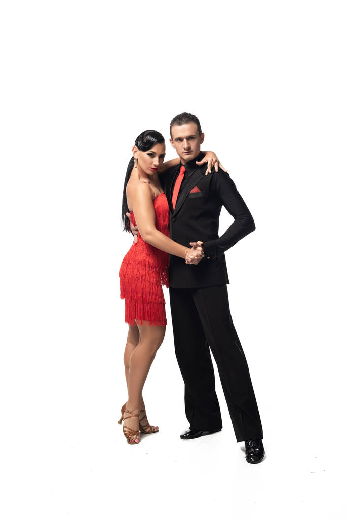 stylish couple of dancers looking at camera while performing tango on white background - Photo, Image