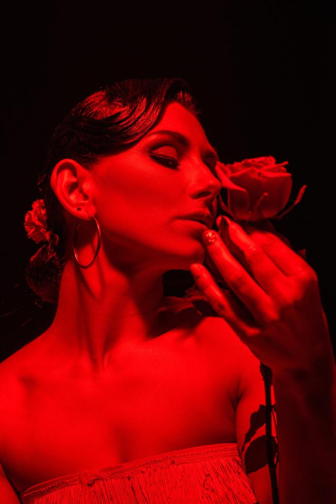 красивий танго танцюрист тримає червону троянду на темному тлі з червоним освітленням
 - Фото, зображення
