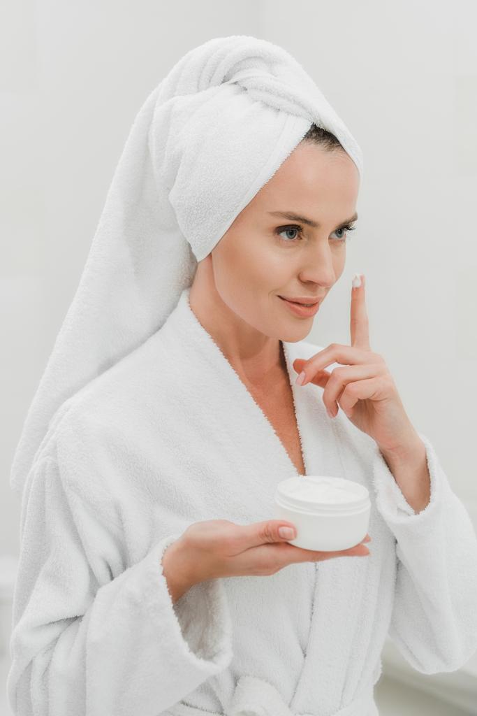 Mulher bonita aplicando creme cosmético no banheiro
  - Foto, Imagem
