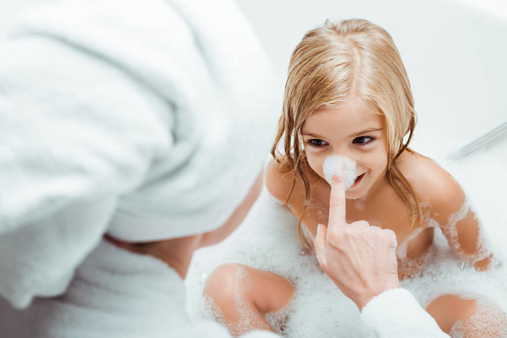 szelektív fókusz anya fürdőkád hab ujj megérintése orr lánya  - Fotó, kép
