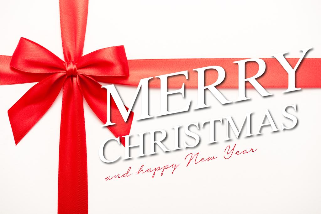 top view of ribbon with red satin bow near merry christmas and happy new year lettering on white  - Photo, Image