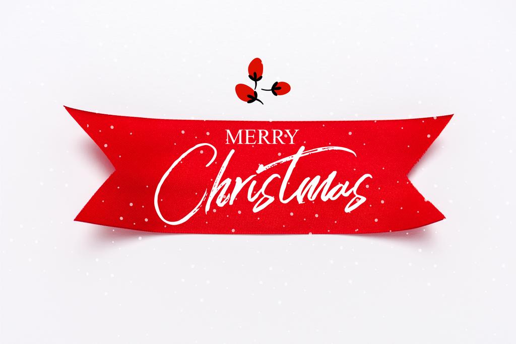 Draufsicht auf rotes Satinband mit frohen Weihnachtsbriefen auf weißem Grund  - Foto, Bild