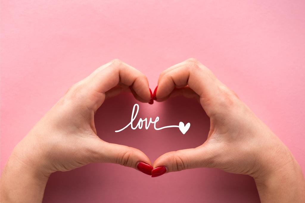 kivágott kilátás nő mutató szív alakú jel a kezét közelében szerelmes betűk rózsaszín  - Fotó, kép