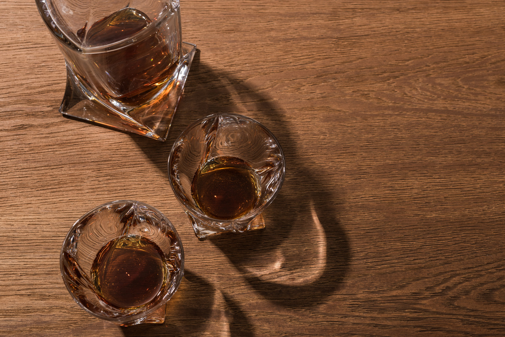 Horní pohled na brandy ve sklenicích a karafě na dřevěném stole - Fotografie, Obrázek