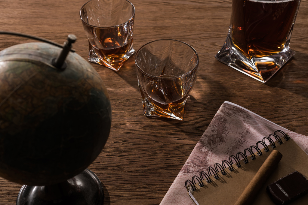 Selektywne skupienie brandy w szklankach z cygarem, kulą i mapą na drewnianym stole - Zdjęcie, obraz