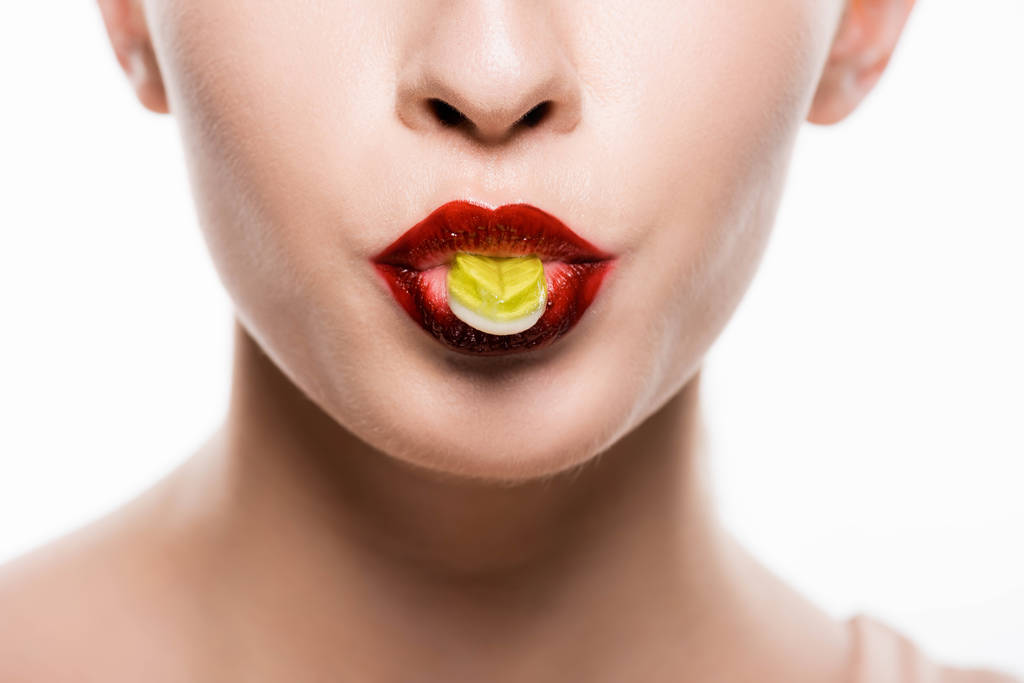 vista ritagliata di donna con labbra rosse che tengono caramelle in bocca isolate su bianco
 - Foto, immagini