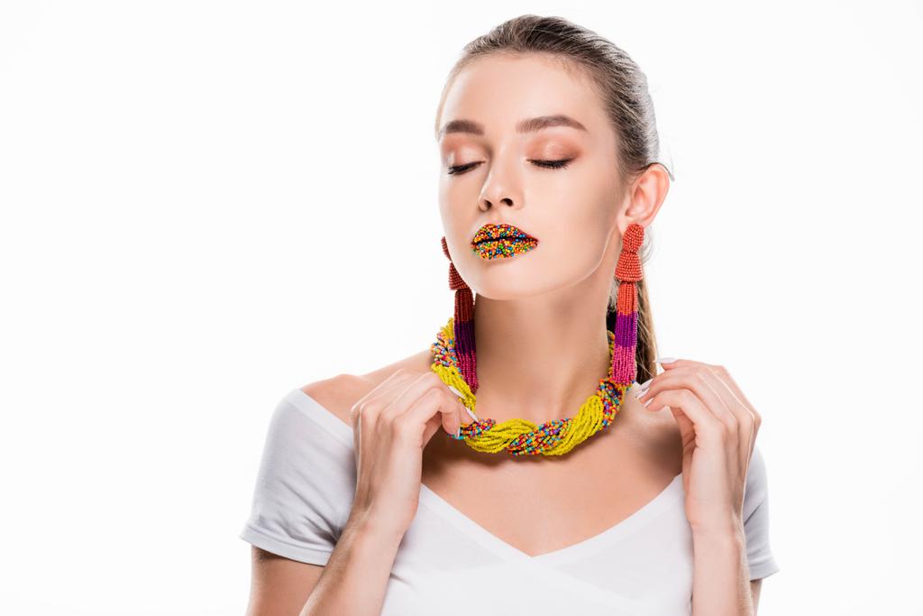 beautiful girl in beaded accessories, with beads on lips, touching necklace isolated on white - Fotoğraf, Görsel