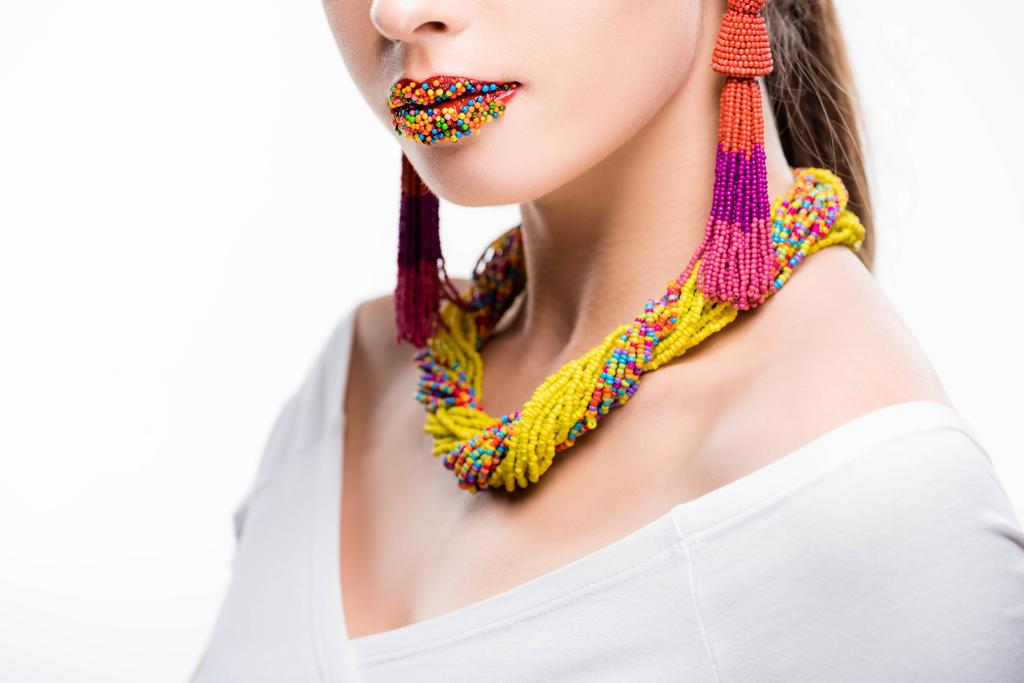 cropped view of girl in beaded necklace and earrings, with beads on lips isolated on white - Photo, Image