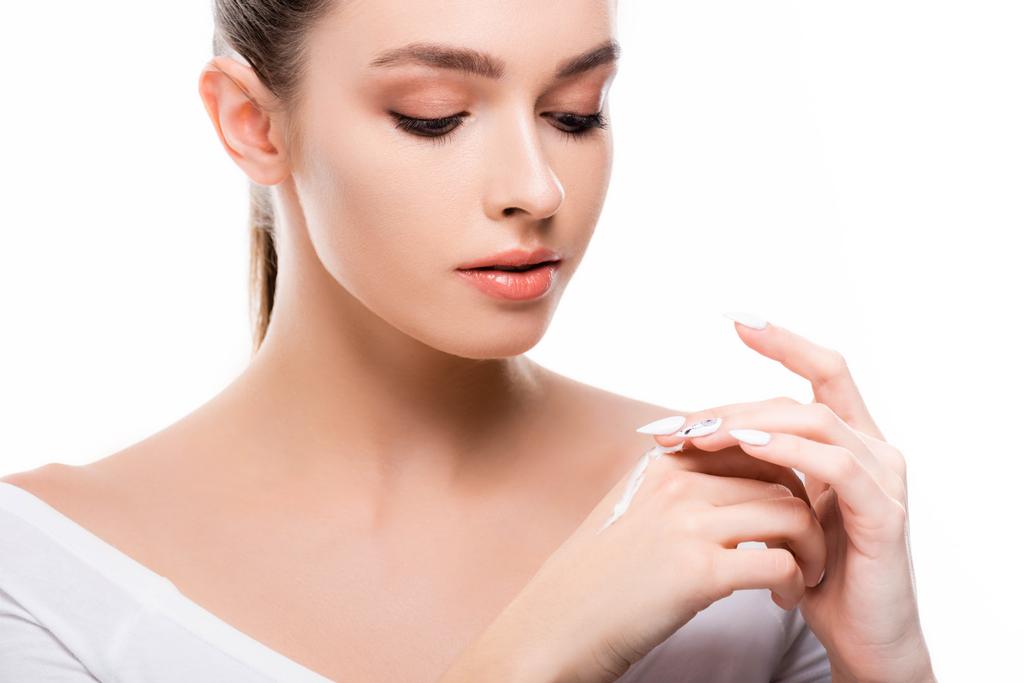 красивая молодая женщина наносит косметический крем на руку изолированы на белом
 - Фото, изображение