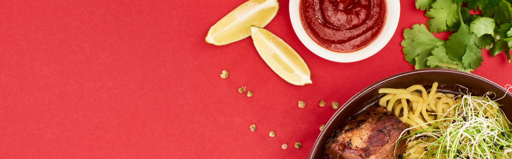 vue du haut des ramen de viande épicée près de la sauce, du persil et de la lime isolés sur rouge, panoramique
 - Photo, image
