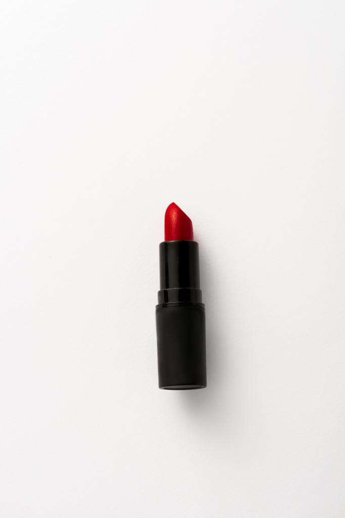 bovenaanzicht van zwarte tube met rode lippenstift op wit met kopieerruimte  - Foto, afbeelding