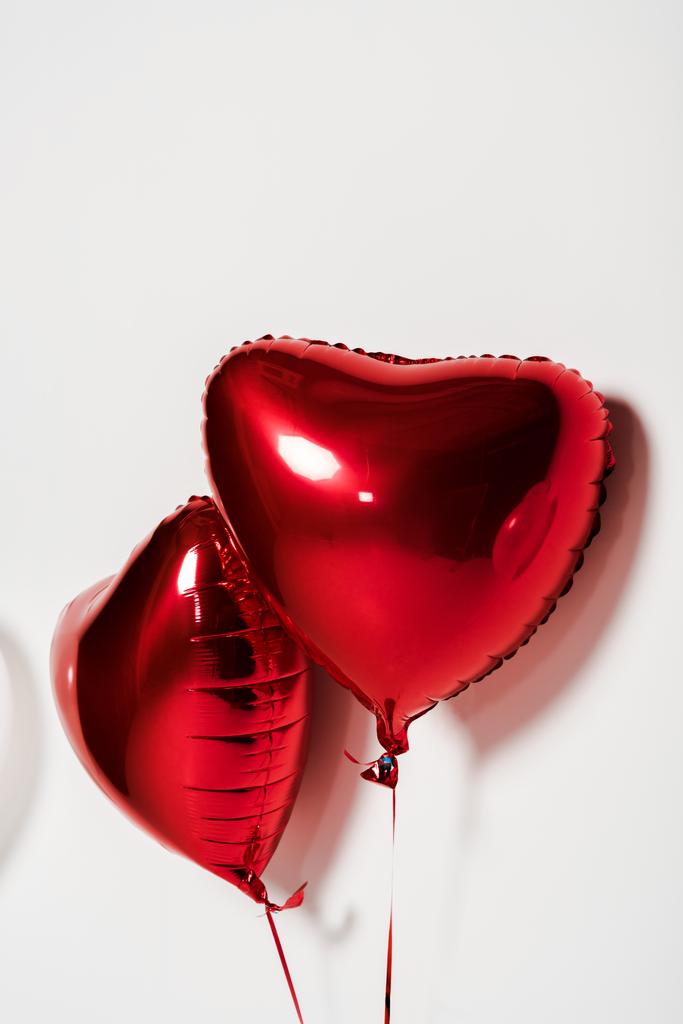 красные и блестящие шары в форме сердца на белом
  - Фото, изображение