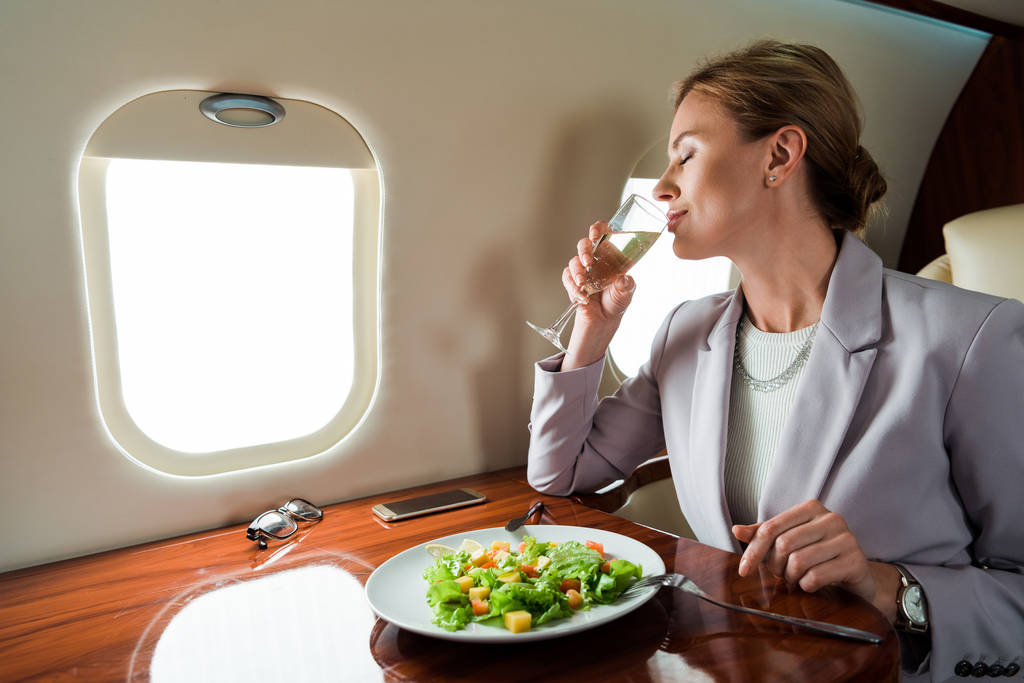 podnikatelka pití šampaňské v blízkosti chutné salát v soukromém tryskáči  - Fotografie, Obrázek