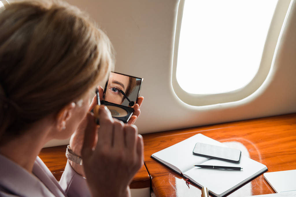 selective focus of businesswoman apply mascara in private plane  - Photo, Image