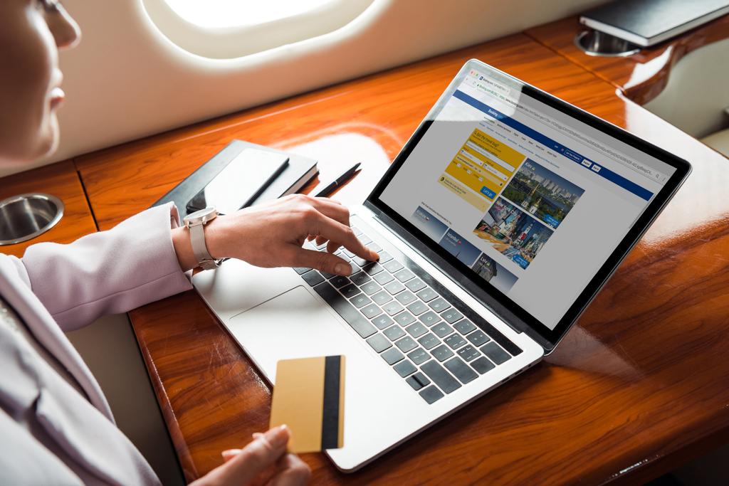vista recortada de la mujer de negocios utilizando el ordenador portátil con el sitio web de reserva, mientras que las compras en línea en avión privado
  - Foto, Imagen