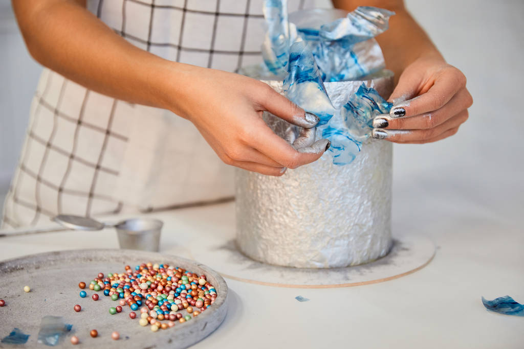 Cropped view of confectioner decorating cake on board - 写真・画像