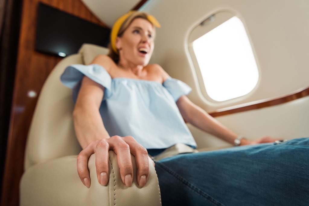 民間航空機でレザーシートを引っ掻く恐怖の女性の選択的焦点  - 写真・画像