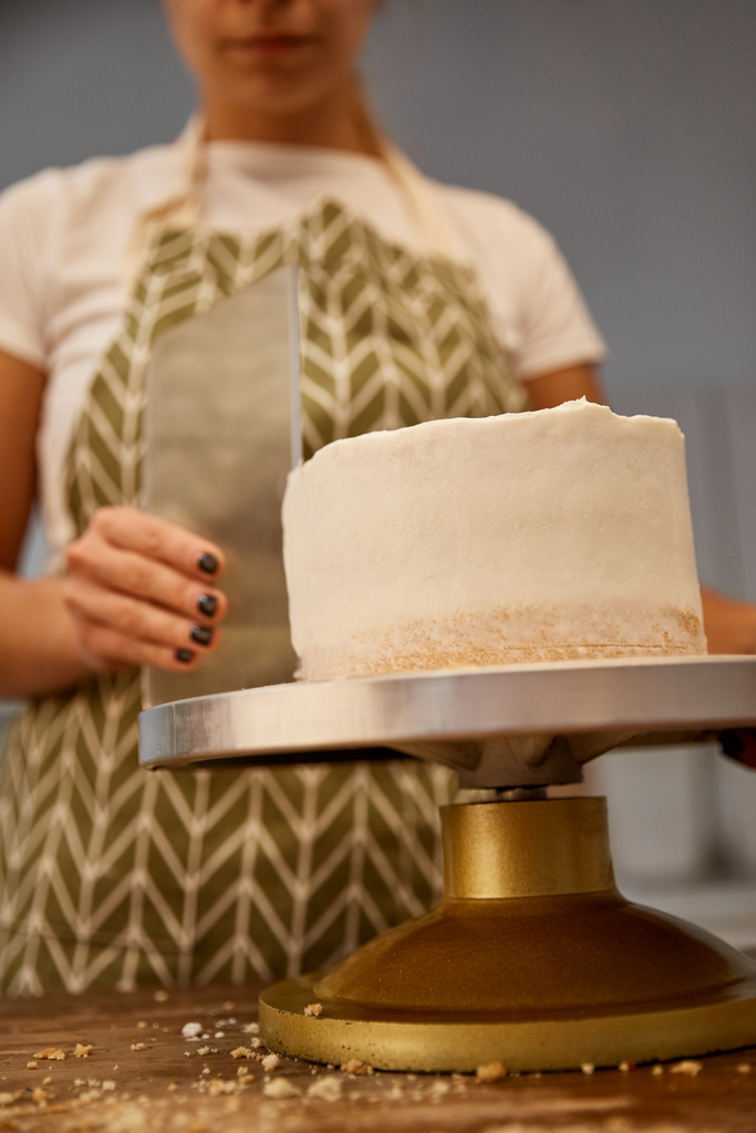 Concentration sélective du confiseur alignant la crème sur le gâteau, vue recadrée
  - Photo, image