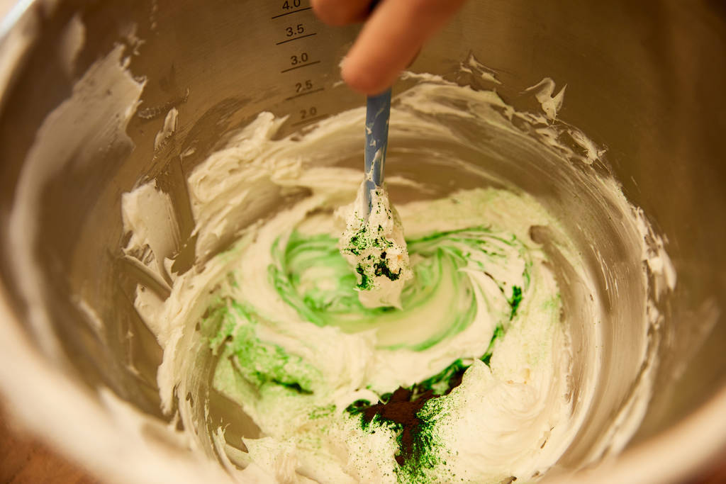 Vue recadrée du confiseur mélangeant crème sucrée dans un bol
 - Photo, image