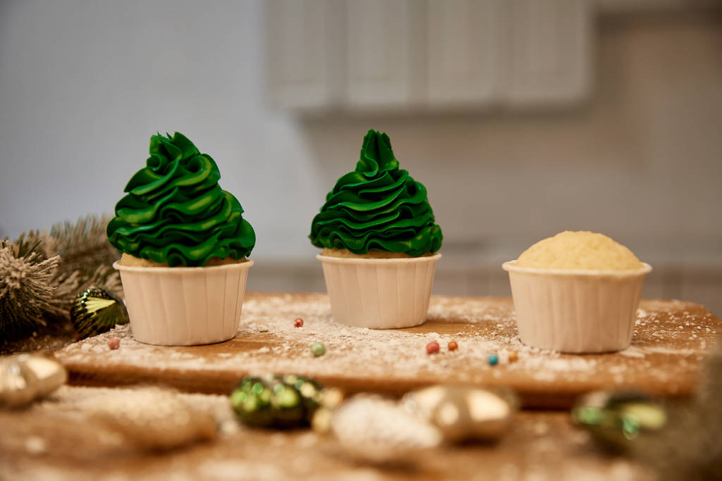 Selective focus of tasty cupcakes with christmas balls and spruce branch on table - Photo, Image