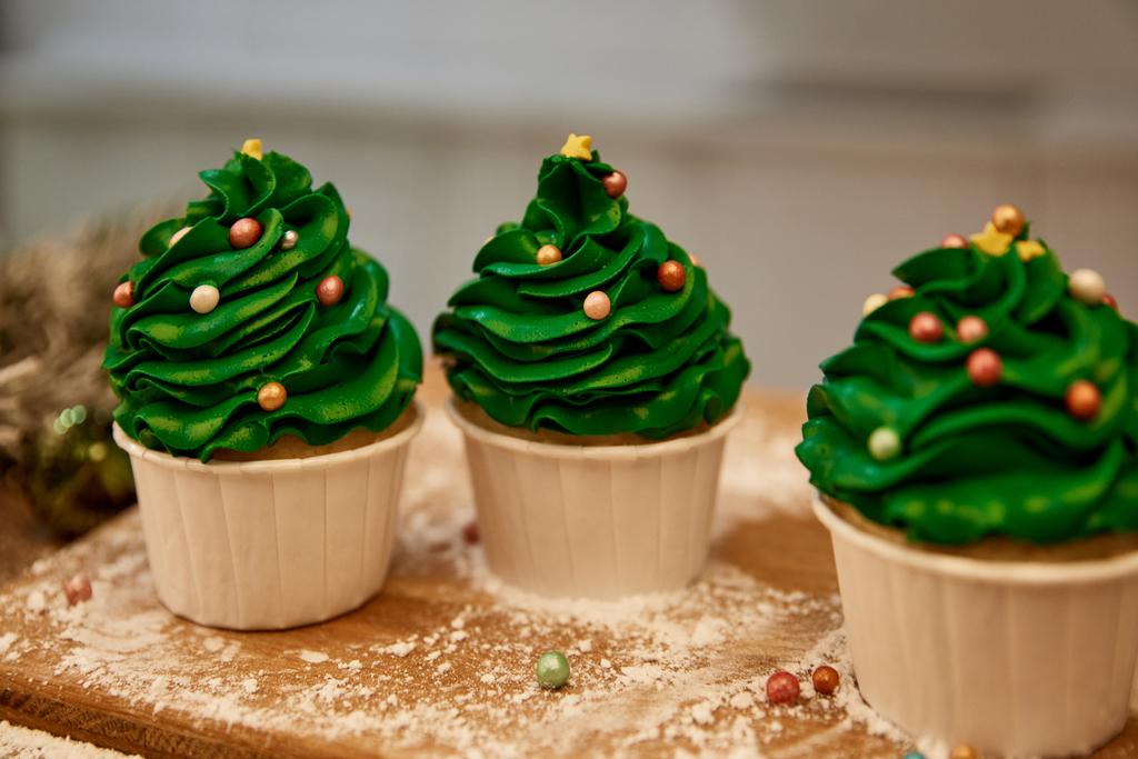 Прикрашені кекси з зеленим кремом і цукровими зморшками на обробній дошці з борошном
 - Фото, зображення
