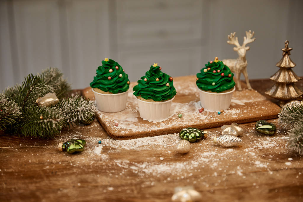 Babeczki z posypką cukru i świąteczne kulki z gałązkami świerku na stole - Zdjęcie, obraz