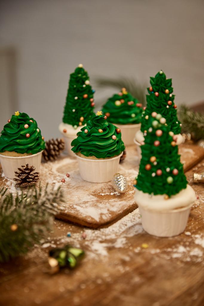 Cupcake con albero di Natale decorato con palline di Natale con ramo di abete rosso e coni sul tavolo
 - Foto, immagini