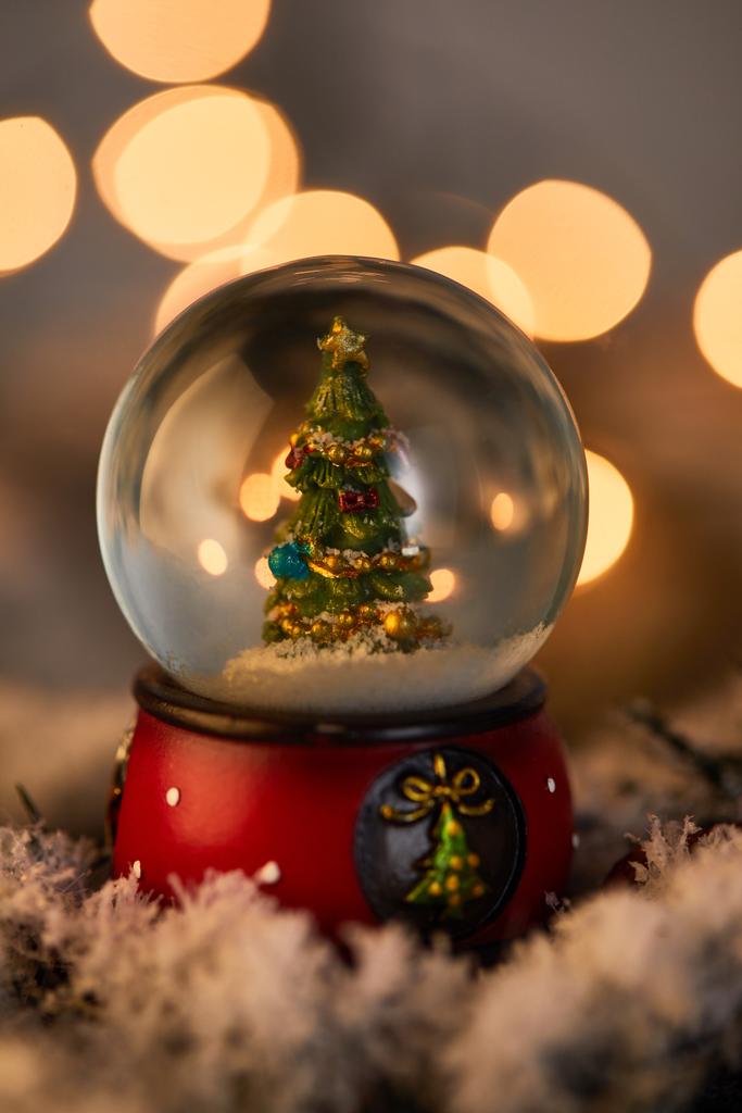 黄金の光で雪の中に立つクリスマスツリーと装飾的な雪玉ボケ - 写真・画像