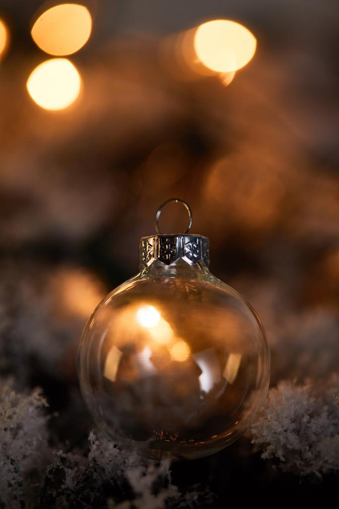 雪の中のスプルースの枝にある透明なクリスマスボール暗い黄色のライト - 写真・画像
