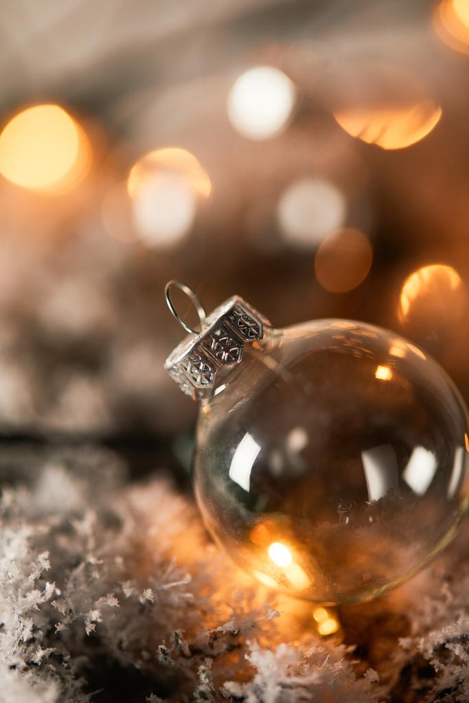 雪の中のスプルースの枝にある透明なクリスマスボールの1つに - 写真・画像