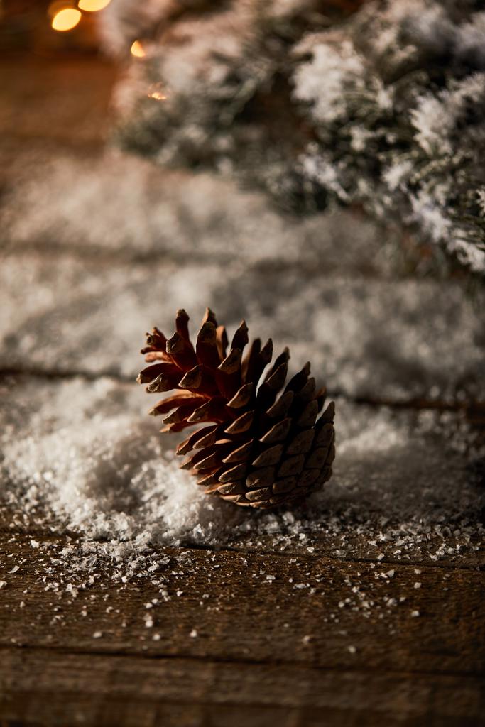 сосновый конус на деревянном столе с еловыми ветвями и снегом на Рождество
 - Фото, изображение