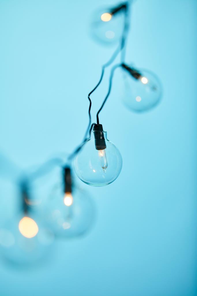 foyer sélectif de guirlande de Noël avec des ampoules transparentes isolées sur bleu
 - Photo, image