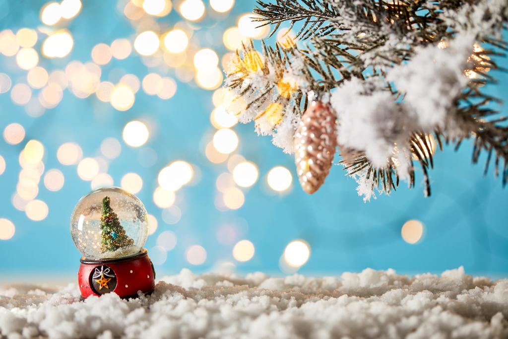 雪と光の中にスプルースの枝がある青の上に立つ雪玉のクリスマスツリーボケ - 写真・画像