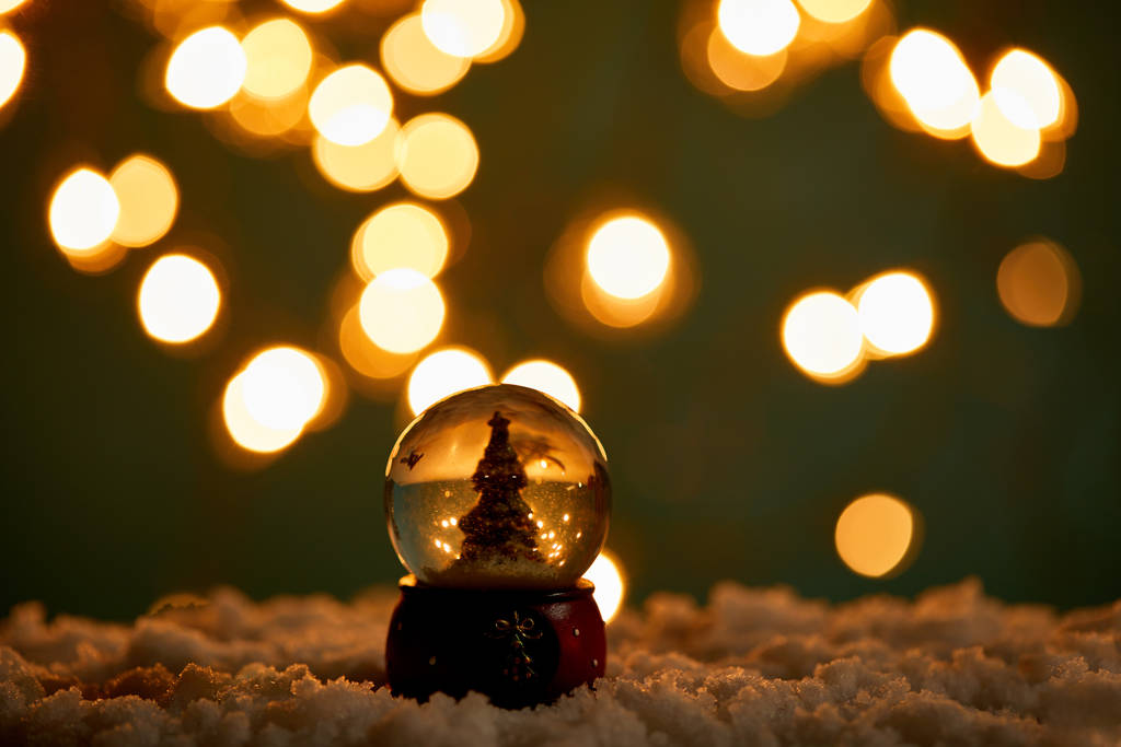 pieni lumipallo joulukuusi seisoo lumessa hämärässä valot yöllä
  - Valokuva, kuva