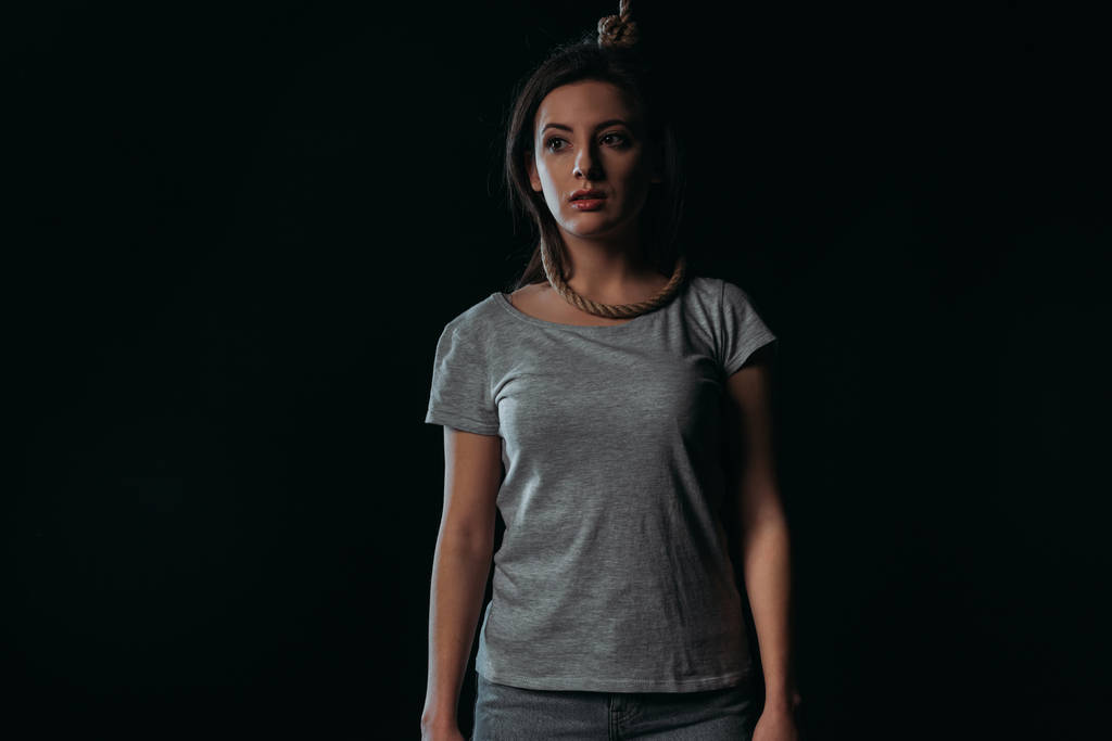frustrado jovem mulher olhando para longe, enquanto de pé com laço no pescoço isolado no preto
 - Foto, Imagem